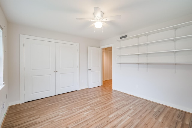 unfurnished bedroom with a ceiling fan, baseboards, visible vents, light wood-style floors, and a closet