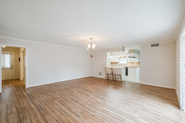 unfurnished living room with light wood finished floors, crown molding, visible vents, and a notable chandelier