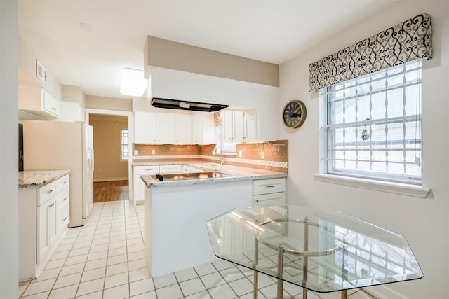 kitchen featuring light tile patterned floors, tasteful backsplash, white refrigerator with ice dispenser, white cabinets, and a peninsula