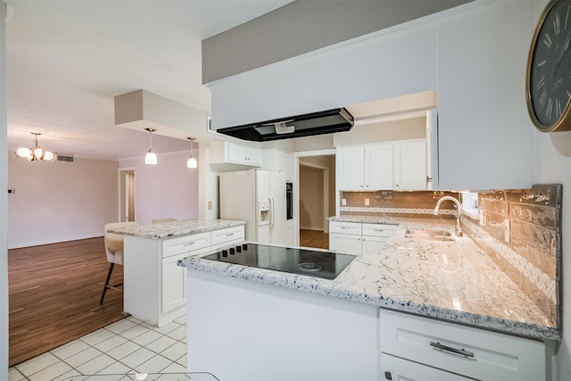 kitchen featuring a peninsula, white refrigerator with ice dispenser, and white cabinets