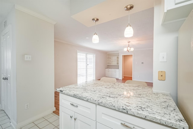 kitchen with a peninsula, white cabinetry, pendant lighting, and ornamental molding