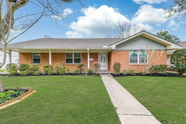 ranch-style home with covered porch, brick siding, roof with shingles, and a front yard