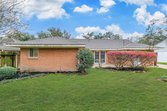 view of front facade featuring a shingled roof, a front yard, and fence