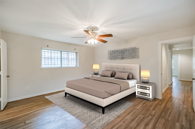 bedroom with a ceiling fan, baseboards, and wood finished floors