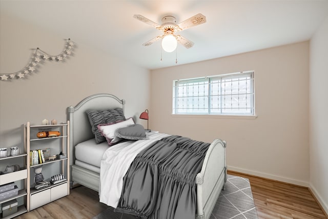 bedroom featuring wood finished floors, a ceiling fan, and baseboards