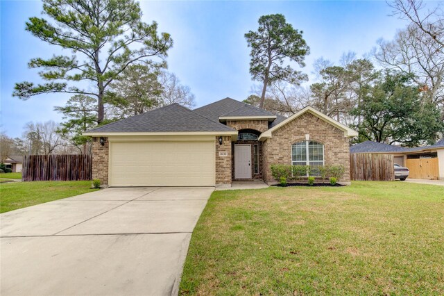 ranch-style home featuring a garage, brick siding, fence, and a front lawn