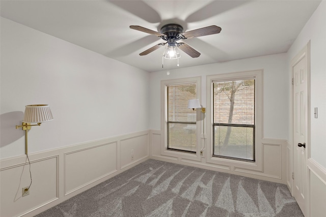 unfurnished room featuring carpet, a wainscoted wall, and a decorative wall