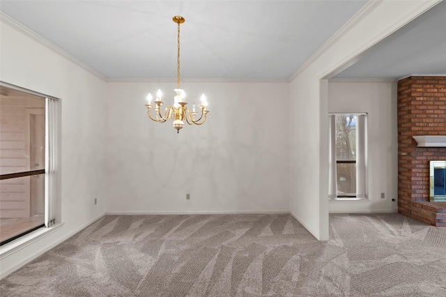 unfurnished dining area with a brick fireplace, carpet flooring, crown molding, and an inviting chandelier