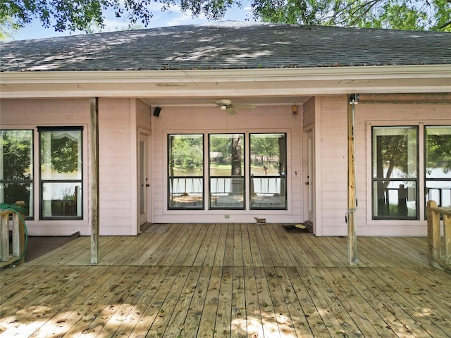 doorway to property with a deck, roof with shingles, and a ceiling fan