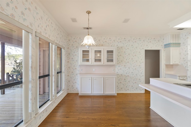 kitchen with visible vents, white cabinets, dark wood finished floors, glass insert cabinets, and wallpapered walls