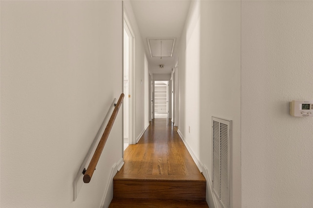 corridor with baseboards, wood finished floors, visible vents, and attic access