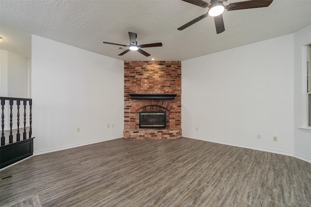 unfurnished living room featuring a textured ceiling, dark wood-type flooring, a fireplace, and baseboards