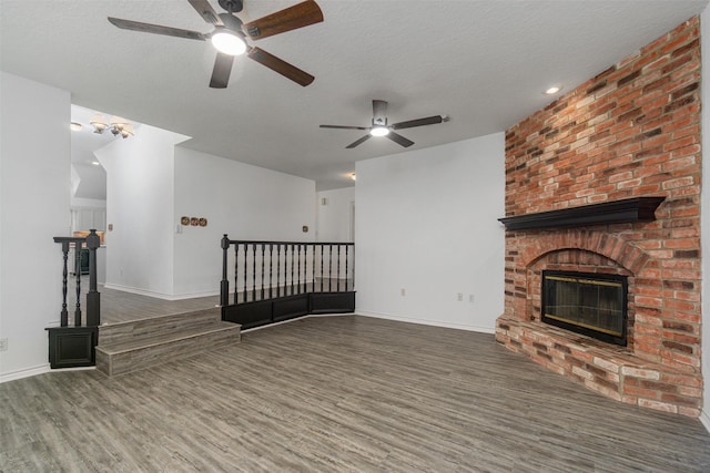 unfurnished living room with a textured ceiling, dark wood-style flooring, a fireplace, and baseboards
