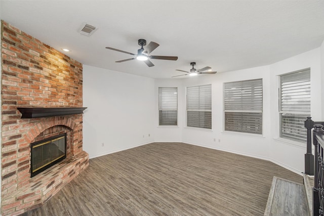 unfurnished living room with a brick fireplace, visible vents, baseboards, and dark wood-style flooring