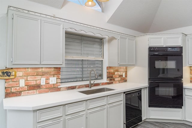 kitchen with tasteful backsplash, white cabinets, light countertops, black appliances, and a sink