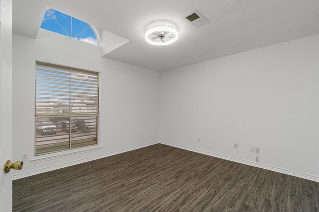 unfurnished room with dark wood-style floors, a textured ceiling, visible vents, and a healthy amount of sunlight
