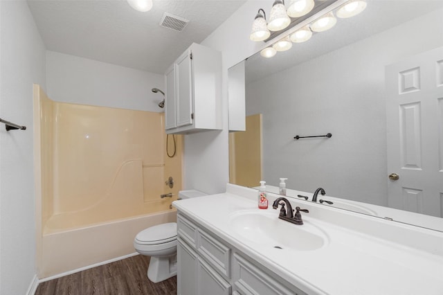 full bathroom featuring toilet, shower / bath combination, wood finished floors, visible vents, and vanity