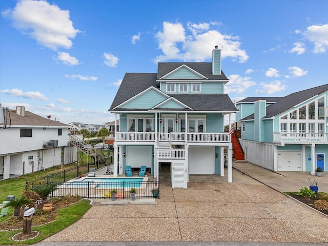 view of front of house featuring fence, stairs, concrete driveway, a fenced in pool, and a patio area