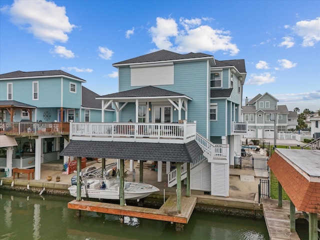 1250 Oahu Dr, Tiki Island, TX 77554 - back of house with boat lift, a residential view, a shingled roof, and a deck with water view
