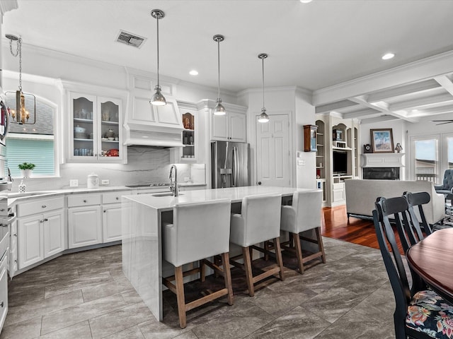 1250 Oahu Dr, Tiki Island, TX 77554 - kitchen featuring decorative backsplash, stainless steel refrigerator with ice dispenser, visible vents, coffered ceiling, and an island with sink