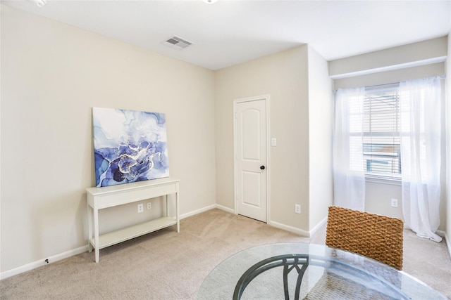 living area featuring light carpet, visible vents, and baseboards