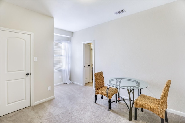 interior space featuring baseboards, visible vents, and light colored carpet