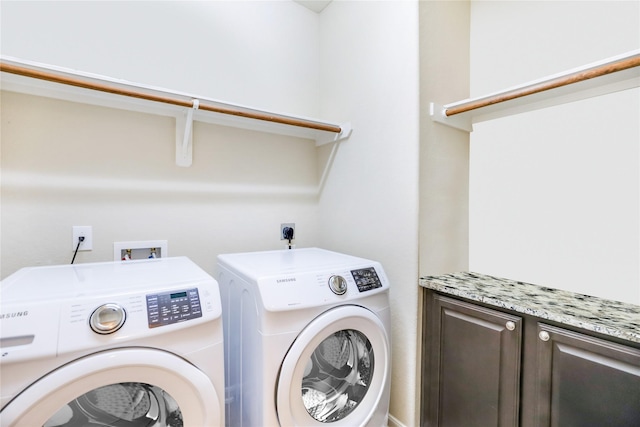 clothes washing area with washing machine and clothes dryer and cabinet space