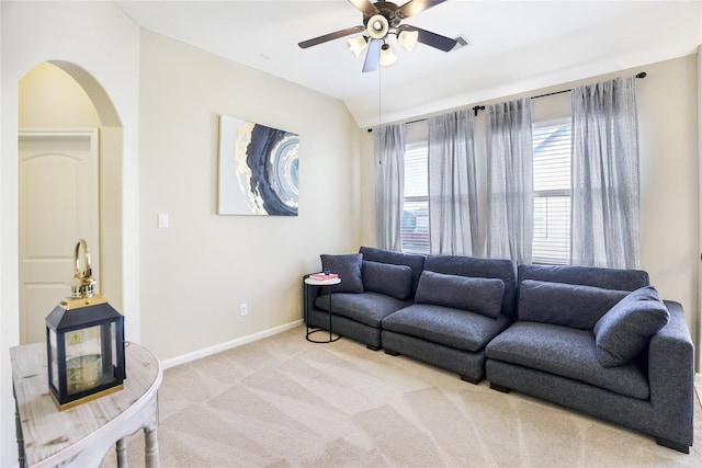 living room featuring light carpet, arched walkways, baseboards, ceiling fan, and vaulted ceiling