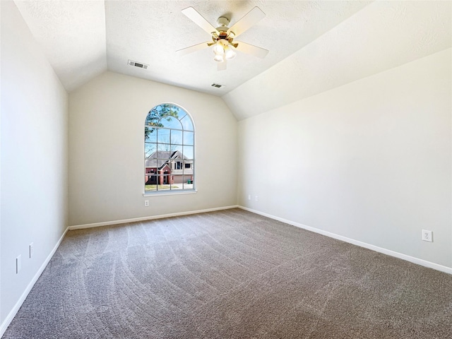 carpeted empty room featuring a textured ceiling, lofted ceiling, and visible vents