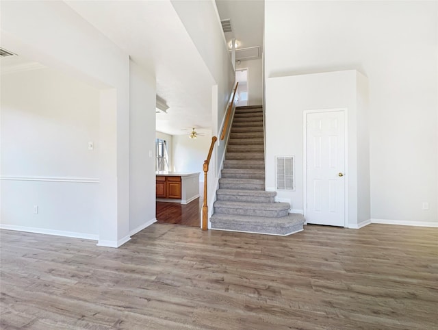 stairway with wood finished floors, visible vents, and baseboards