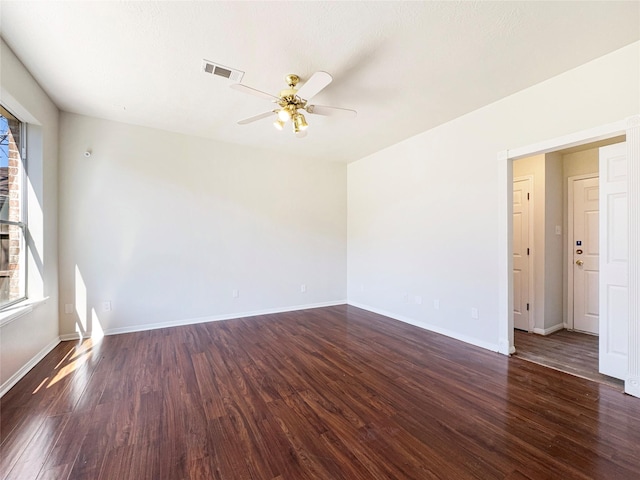 spare room featuring dark wood-type flooring, visible vents, baseboards, and a ceiling fan