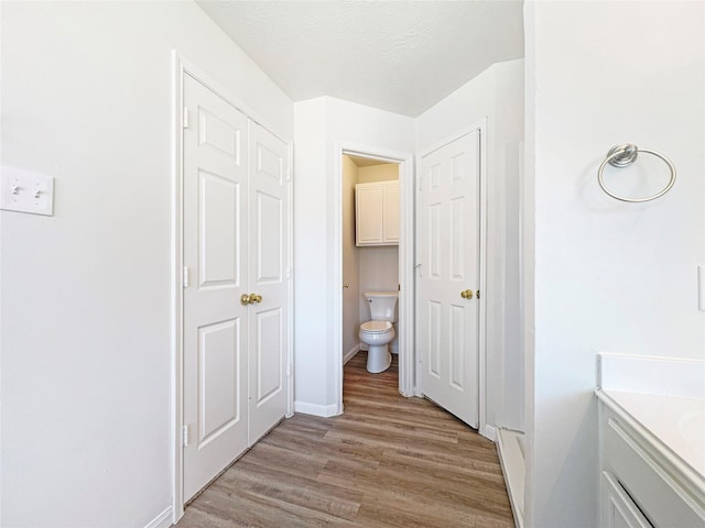 bathroom featuring baseboards, toilet, wood finished floors, a textured ceiling, and vanity