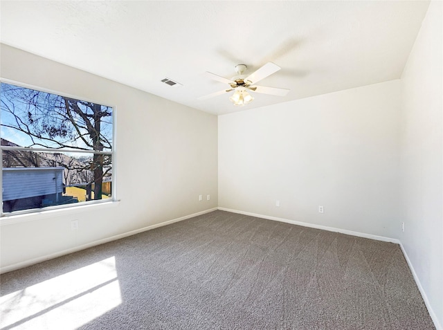 carpeted empty room featuring baseboards, visible vents, and ceiling fan