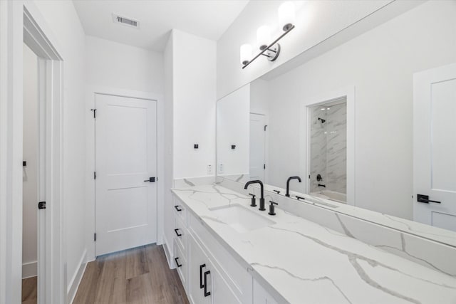 bathroom with vanity, bathing tub / shower combination, wood finished floors, and visible vents