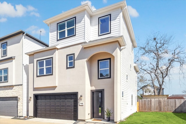 view of property featuring a front yard, fence, an attached garage, and stucco siding