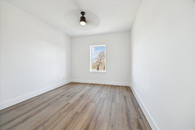 spare room with ceiling fan, light wood finished floors, and baseboards