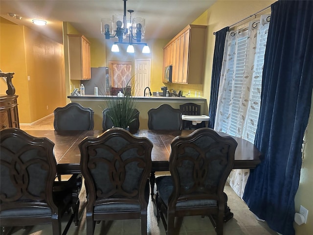 interior space with light brown cabinetry, stainless steel microwave, freestanding refrigerator, and a notable chandelier