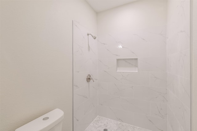 full bathroom with a tile shower and toilet