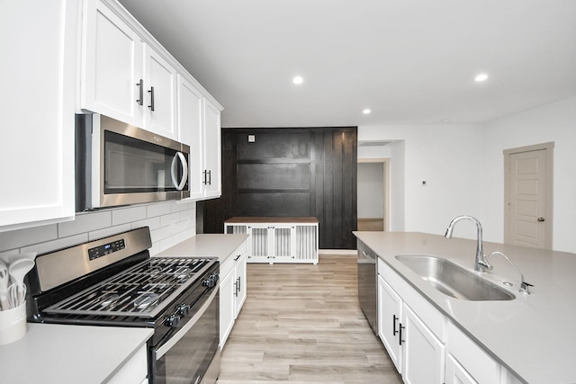 kitchen with stainless steel appliances, light countertops, a sink, and white cabinetry