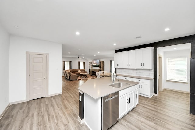 kitchen featuring a sink, open floor plan, light countertops, stainless steel dishwasher, and an island with sink