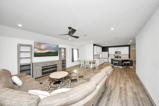 living area featuring ceiling fan, recessed lighting, a fireplace, visible vents, and light wood finished floors