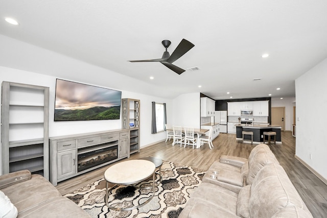 living room with a fireplace, light wood finished floors, recessed lighting, visible vents, and ceiling fan