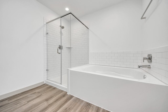 bathroom featuring a garden tub, recessed lighting, wood finished floors, and a shower stall