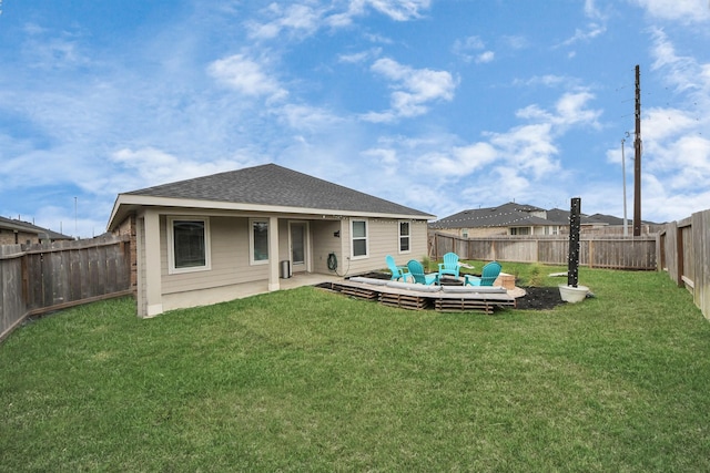 rear view of property with a yard, roof with shingles, and a fenced backyard