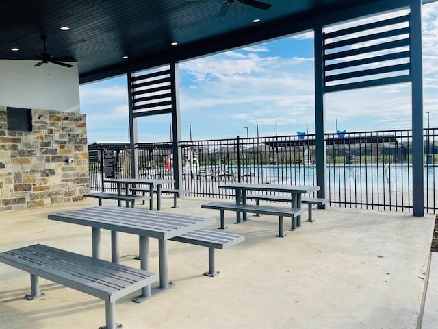 view of patio / terrace featuring a water view, fence, and a ceiling fan