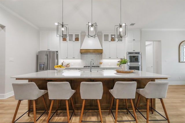 kitchen featuring glass insert cabinets, stainless steel appliances, and a large island with sink