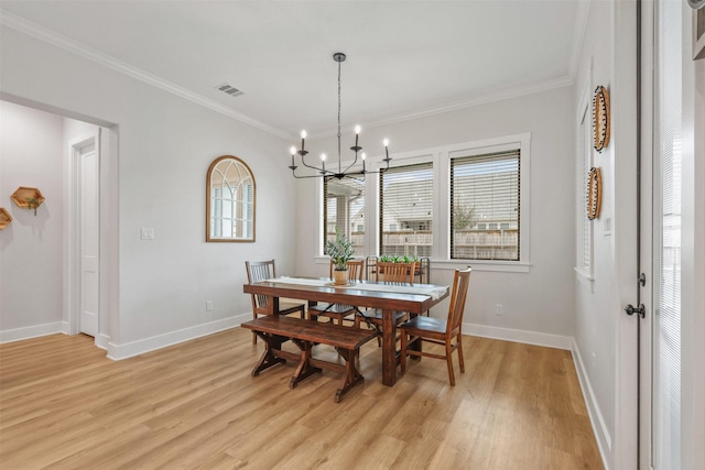 dining room featuring light wood finished floors, visible vents, and crown molding