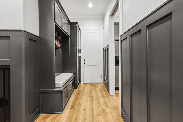 mudroom featuring a wainscoted wall, ornamental molding, and light wood-style flooring