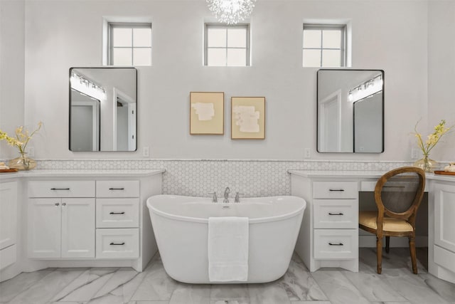 bathroom featuring marble finish floor, a wainscoted wall, a soaking tub, and vanity