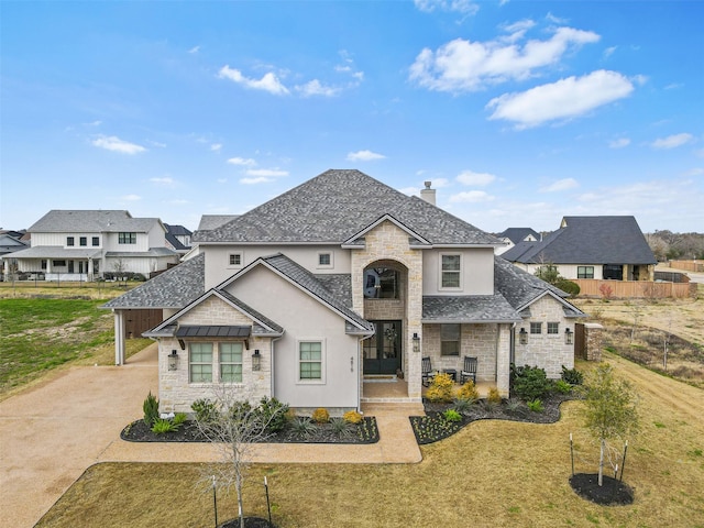 french provincial home featuring a residential view, stone siding, a chimney, and a front lawn